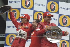 Schumi and Rubinho, each with cup